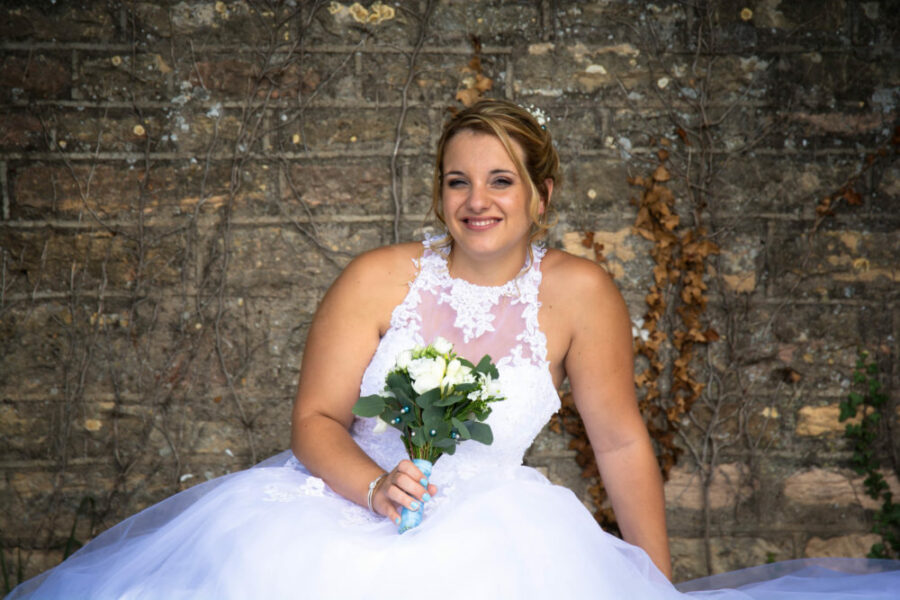 photo d'une femme mariée, robe blanche et bouquet à la main