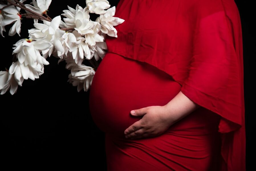 photo d'une femme enceinte portant une robe rouge et des fleurs blanches